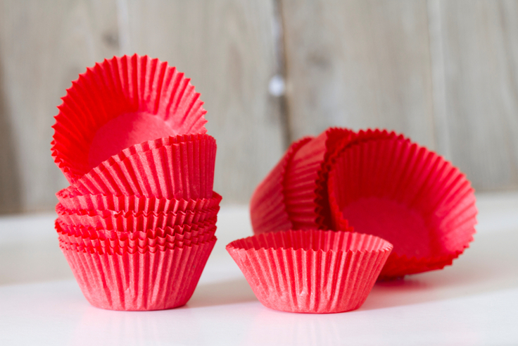 Rote Muffinförmchen aus Papier liegen aufgestapelt nebeneinander.